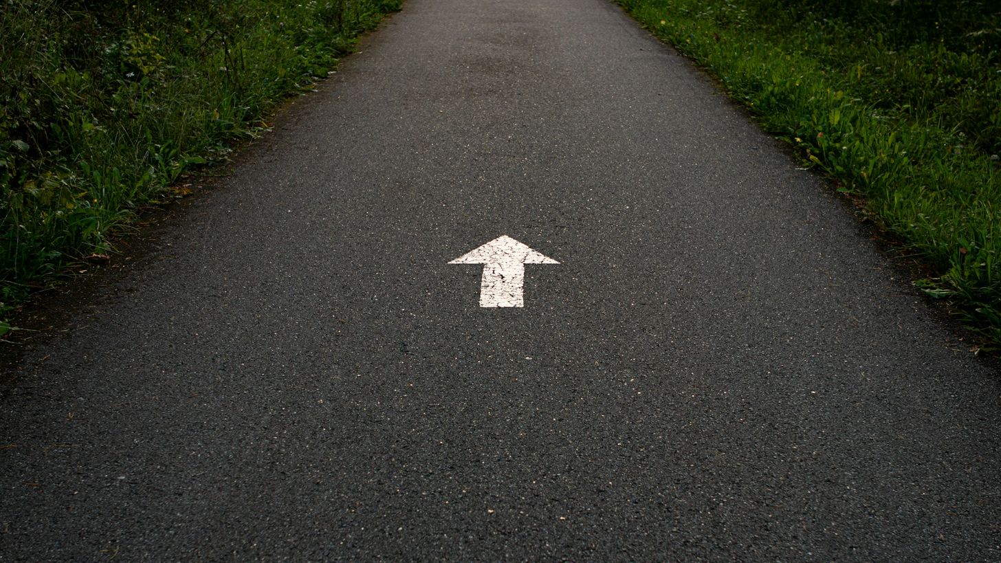 Flèche blanche peinte sur une route.