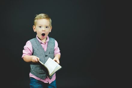 Un enfant tenant une Bible dans les mains avec une expression d'étonnement