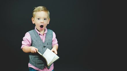 Un enfant tenant une Bible dans les mains avec une expression d'étonnement