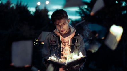 Jeune homme regardant un livre brûler entre ses mains